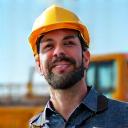 Construction foreman smiling on a job site with new excavator in background
