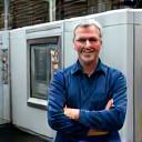 Successful small factory owner smiling next to new CNC machine